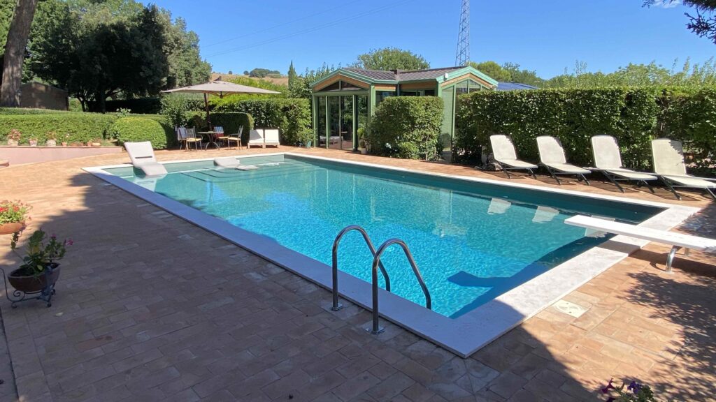 Piscina a skimmer a Perugia integrata nel giardino con bordo e solarium Tecnoacque